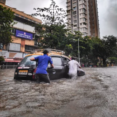 two men push a car through a flooded street